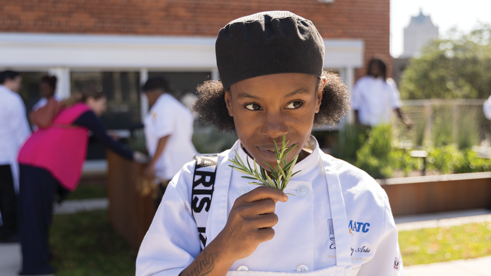 Student smells and holds fresh rosemary