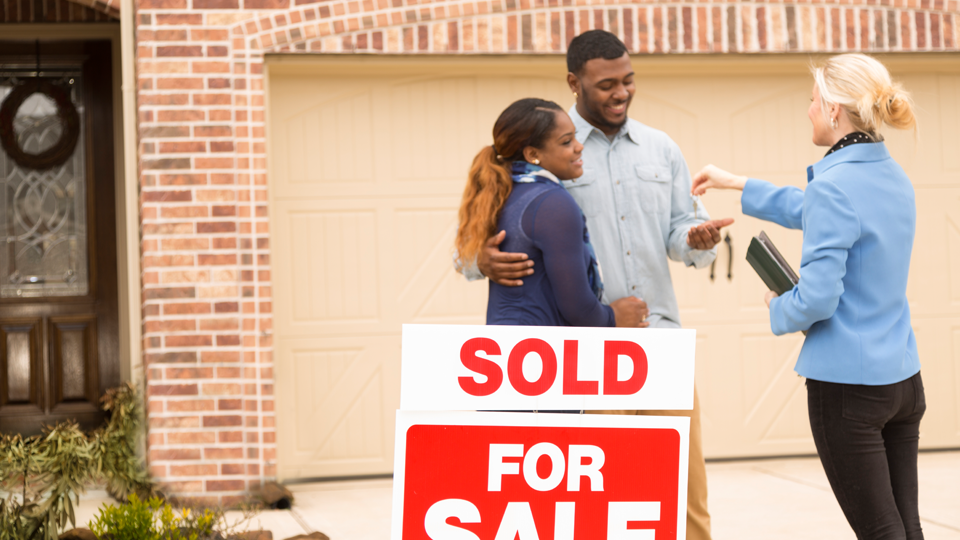 real estate broker handing keys to new home owners