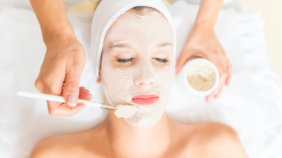 Student applying facial treatment to a spa visitor