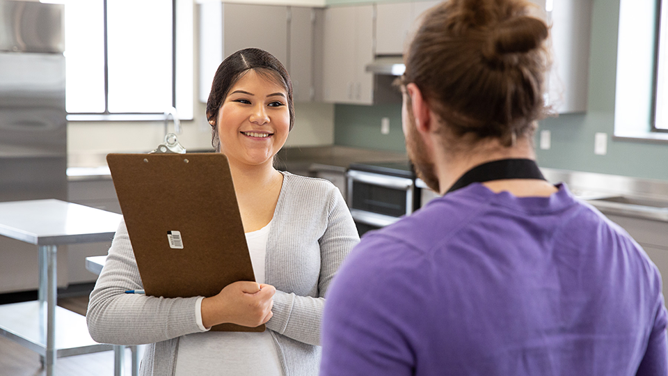 Woman with clipboard consulting with man