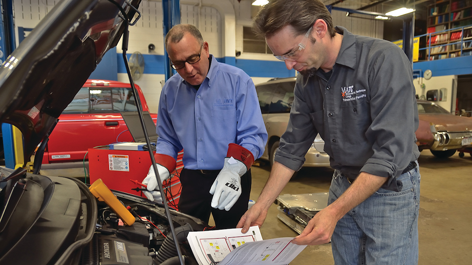 student and instructor working on car