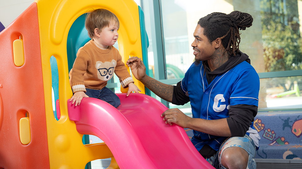 male childcare worker and boy on slide 