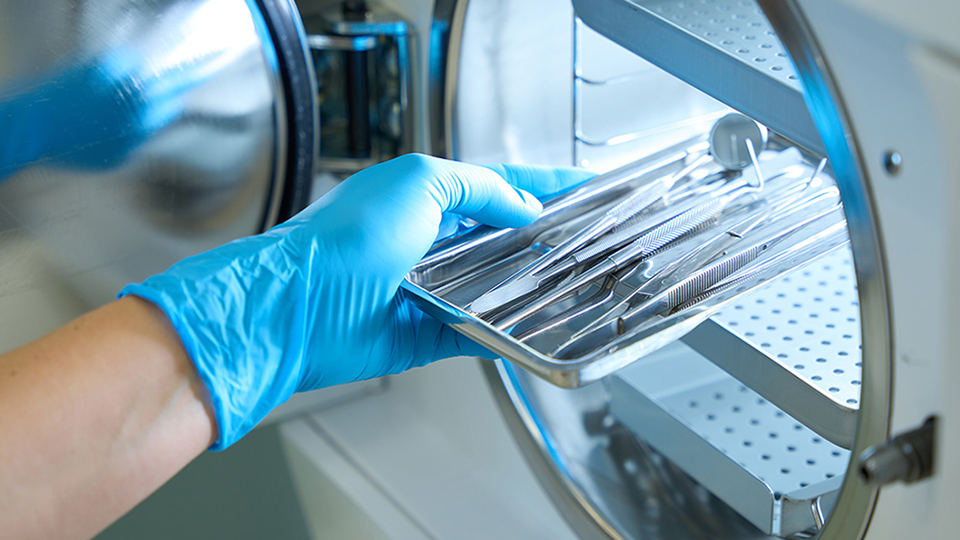 gloved hand preparing surgical instruments for sterilization