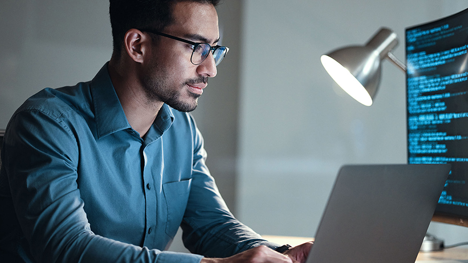 man with glasses working on a laptop