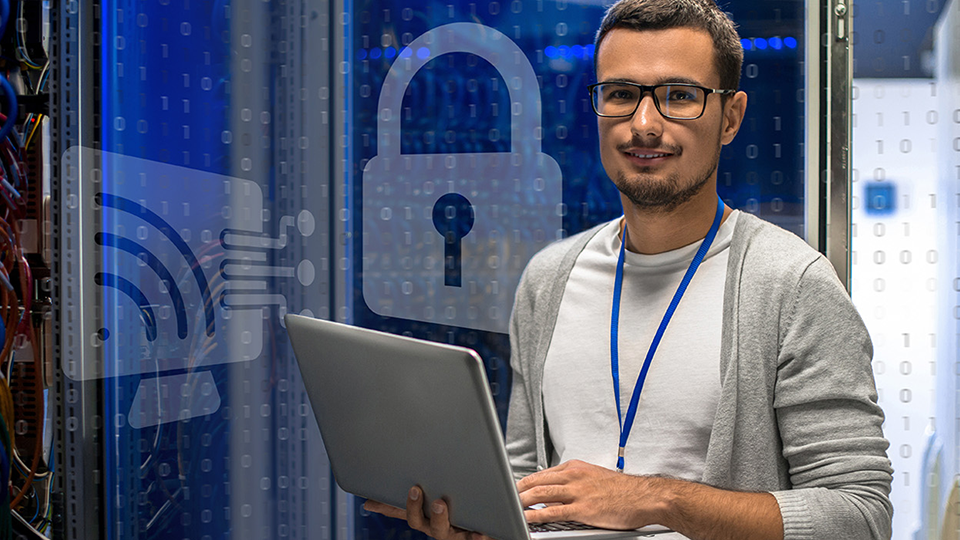 man holds his laptop in IT server room