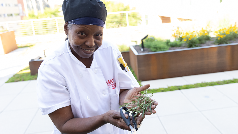 Student holding fresh cut herbs in outstretched hands 